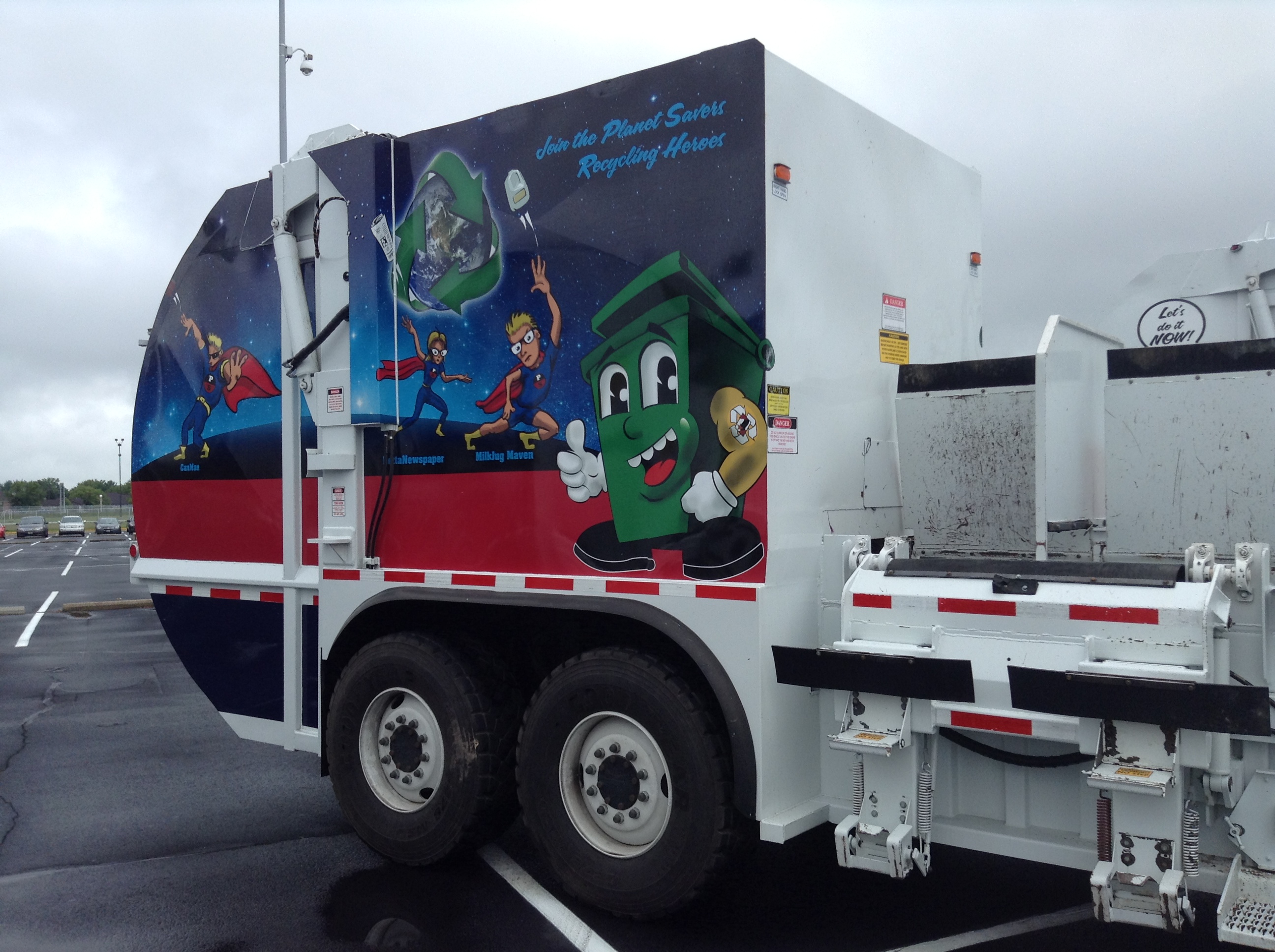 A trash truck with a cartoon dumpster on the side
